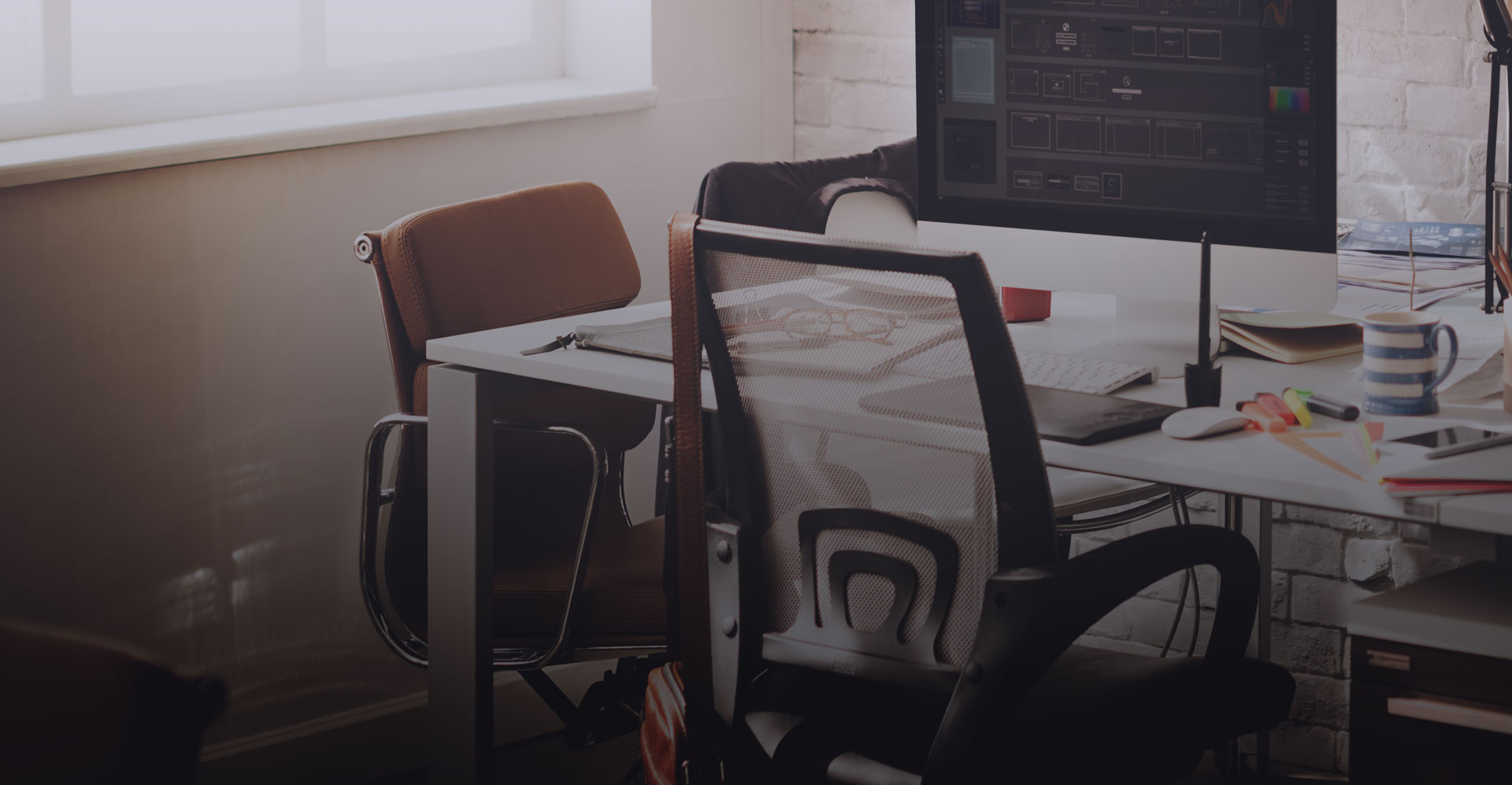 mesh chair in front of a desk with pens, a mug and a computer